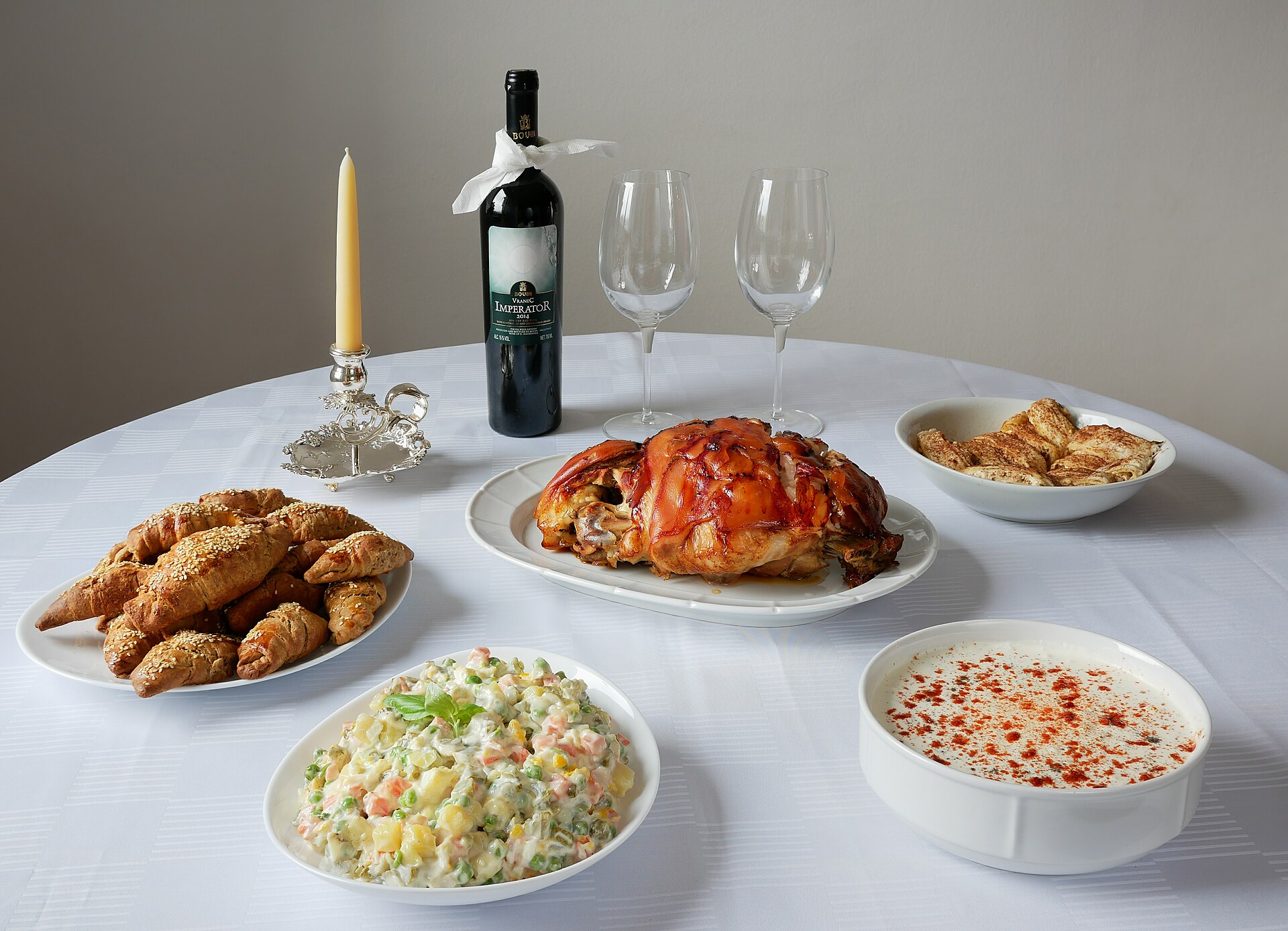 Christmas table (Cuisine of Serbia); grilled pork, Olivier salad (also called Russian salad), tzatziki salad, red wine Vranac, kifli and strudel sweets.