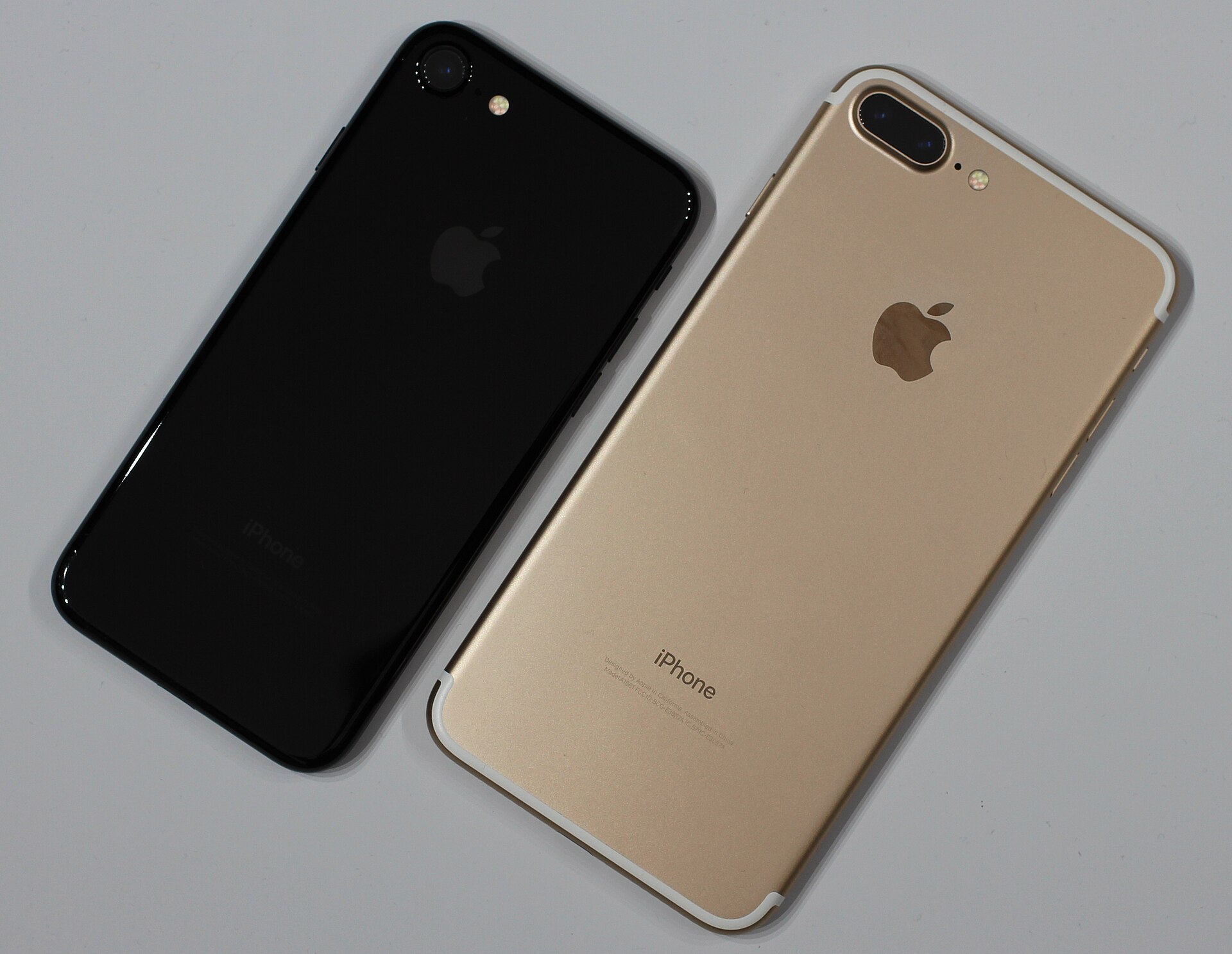 Photo of an Apple iPhone 7 in "jet black" and an Apple iPhone 7 Plus in "gold".