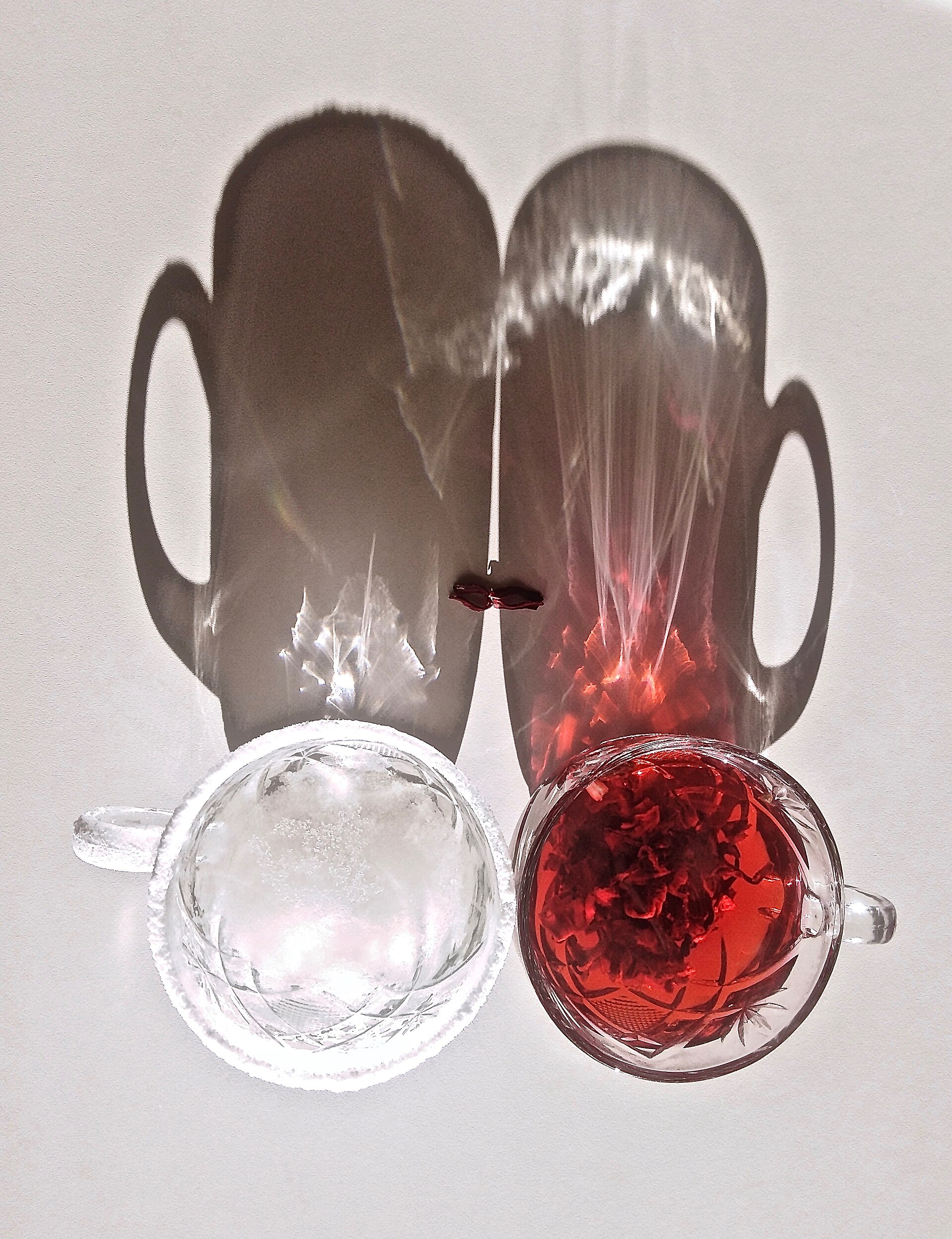 Hibiscus tea and iced water with shadows from cups.
